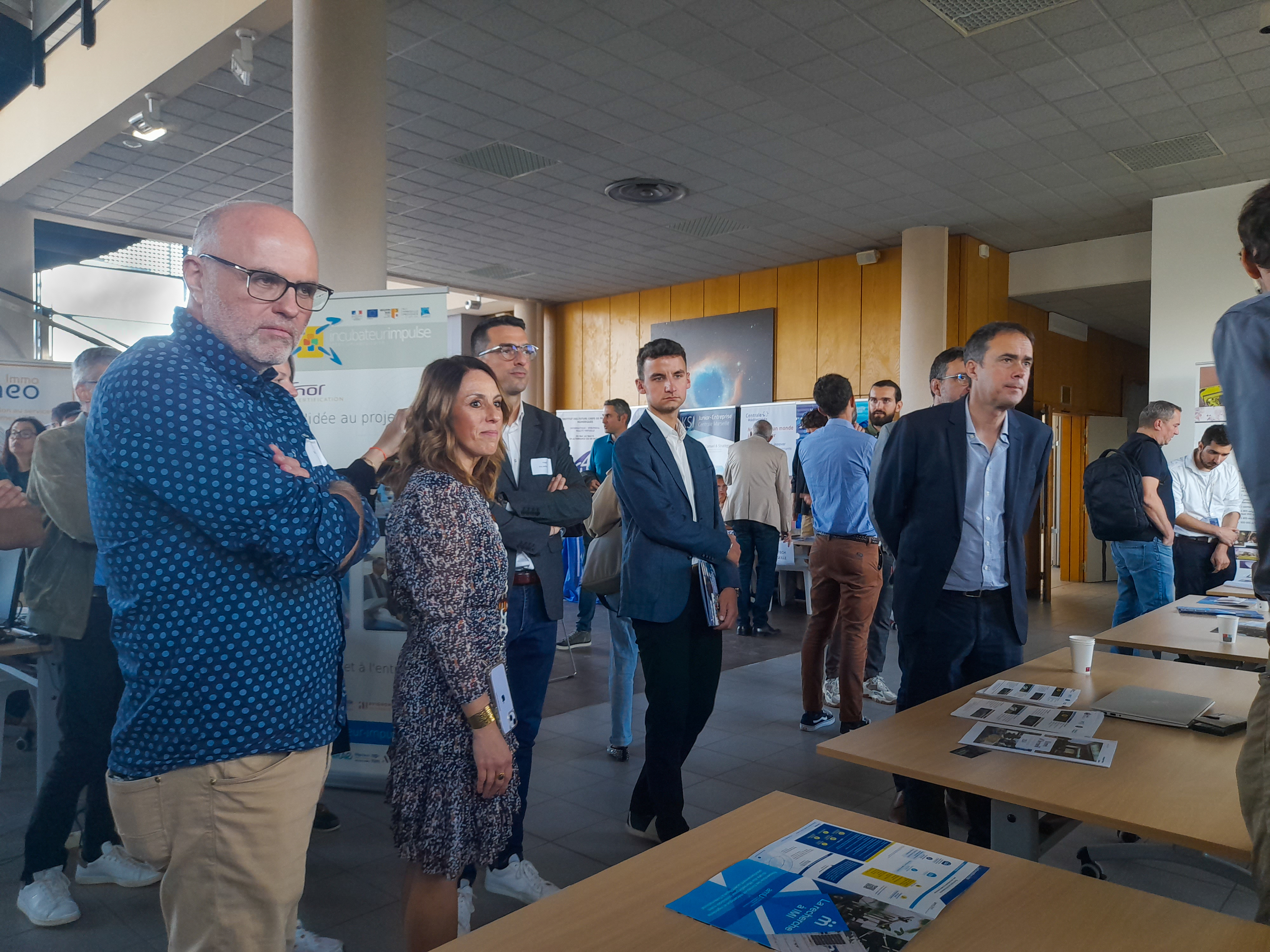 Eric Serre, directeur de l'institut de Mécanique et d'Ingénierie, Arnaud Mercier maire de Venelles et d'autres visiteurs devant un stand de la Business Rencontre du technopôle 2024